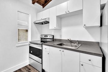 Miami apartment for rent - A modern kitchen with white cabinets and stainless steel appliances.