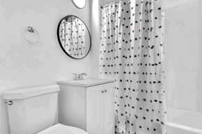 Miami apartment for rent - A white bathroom with a tub, sink, and shower curtain.