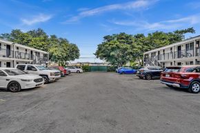 Miami apartment for rent - A parking lot with several cars parked in front of apartment buildings.