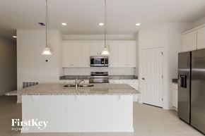 Bartow house for rent - a kitchen with white cabinets and a granite counter top