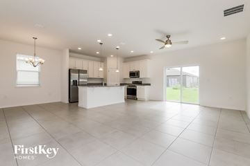 Bartow house for rent - A spacious kitchen and living room with white tiled floors and a ceiling fan.