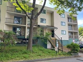 Richmond apartment for rent - A tree with green leaves is in front of a beige apartment building.