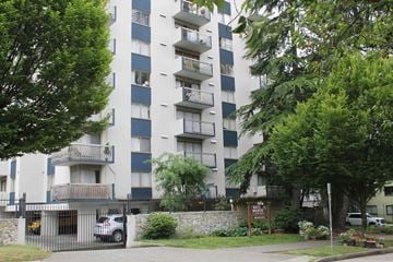 Vancouver apartment for rent - A tall apartment building with balconies and a gate in front.
