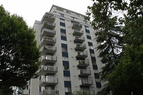 Vancouver apartment for rent - A tall apartment building with balconies and trees in the foreground.