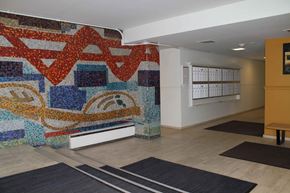 Vancouver apartment for rent - A large mosaic wall in a hallway with a bench and rugs on the floor.