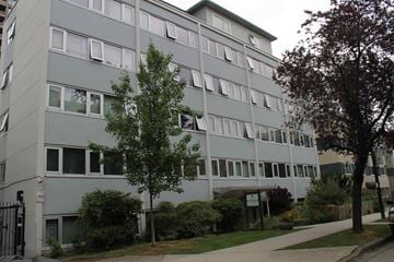 Vancouver apartment for rent - A grey building with a tree in front of it.
