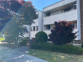 Vancouver apartment for rent - A building with a white facade and a green bush in front.