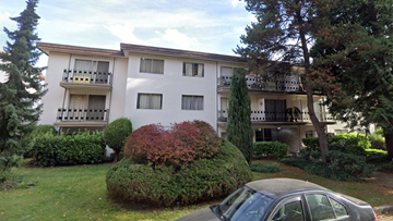 Vancouver apartment for rent - A car is parked in front of a white building with balconies.