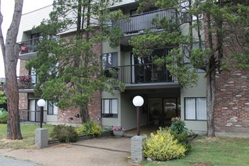 Vancouver apartment for rent - A building with a balcony and a small garden in front.