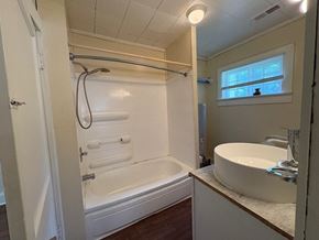 Stantonsburg house for rent - A white bathroom with a tub, sink, and window.