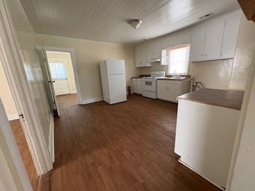 Stantonsburg house for rent - A kitchen with white cabinets and a wooden floor.