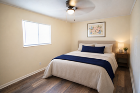 Knoxville apartment for rent - A bedroom with a bed, a ceiling fan, and a small nightstand.