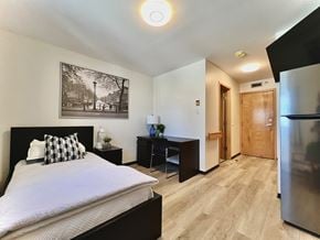 Regina apartment for rent - A bedroom with a bed, nightstand, and a framed picture on the wall.