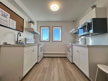 Regina apartment for rent - A kitchen with white cabinets and a microwave above the stove.