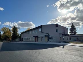 Regina apartment for rent - A large building with a grey roof and a parking lot in front.