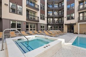 West Jordan apartment for rent - a pool with yellow chairs in front of an apartment building
