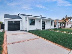 Los Angeles house for rent - A white house with a black garage door is situated in a grassy area.