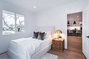 Los Angeles house for rent - A bedroom with a large bed and a wooden cabinet with a lamp on it.