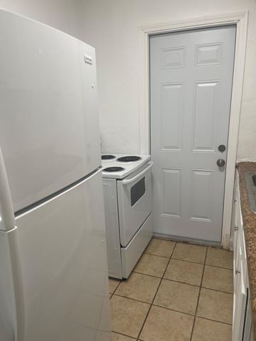 Fort Myers apartment for rent - A white refrigerator is in a kitchen next to a white door.