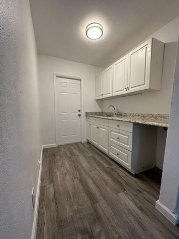 Fort Myers apartment for rent - A kitchen with white cabinets and a wooden floor.