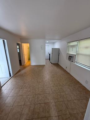 Fort Myers apartment for rent - A spacious room with tile flooring and a refrigerator in the corner.