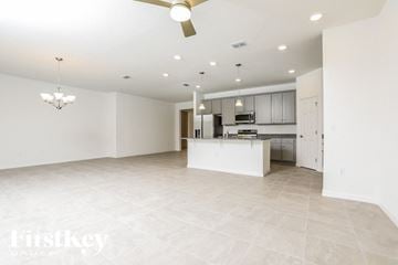 Kissimmee house for rent - a large kitchen and living room with white tile flooring and white cabinets