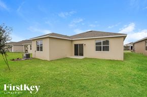 Kissimmee house for rent - a beige house with a grassy yard in front of it