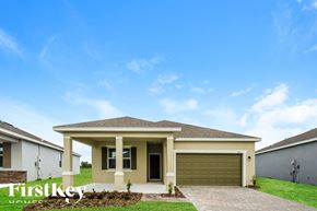 Kissimmee house for rent - a house with a garage door in front of a green lawn