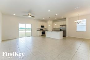 Kissimmee house for rent - an open kitchen and living room with white tile flooring and a large white island