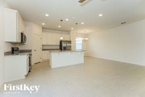 Kissimmee house for rent - an open kitchen and living room with white cabinets and tile flooring