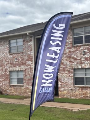 Bartlesville apartment for rent - A purple banner with the words "Now Leasing" is displayed in front of a brick building.
