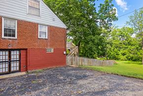 Nashville apartment for rent - A red brick house with a wooden fence and green trees in the background.