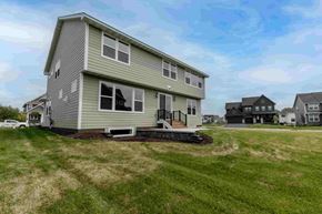 Hugo house for rent - a house on the corner of a grassy yard with other houses in the background