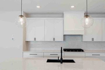 Hugo house for rent - an all white kitchen with white cabinets and a black sink