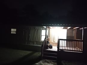 Warrenville house for rent - A dark scene with a lit window and a bench.