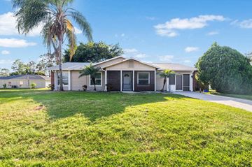 Port Saint Lucie house for rent - A house with a green lawn and a palm tree in front.