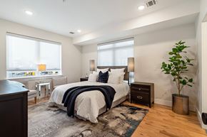 Newark apartment for rent - A bedroom with a large bed and a plant.