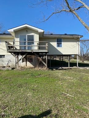 Knob Noster house for rent - A house with a balcony is surrounded by grass and trees.