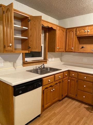 Knob Noster house for rent - A kitchen with wooden cabinets and a white countertop.