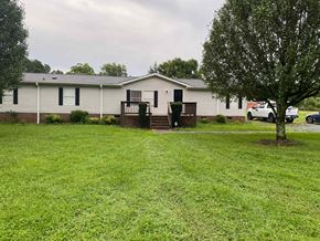 Concord house for rent - a white mobile home with a yard and a tree