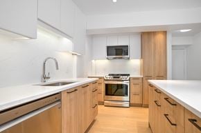 Hampstead apartment for rent - a kitchen with wooden cabinets and white counter tops and a sink
