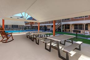 Groves apartment for rent - a patio with benches and tables next to a pool
