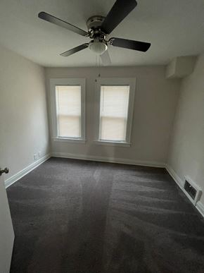 Lima apartment for rent - an empty room with a ceiling fan and two windows