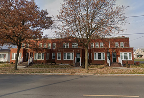 Lima apartment for rent - A red brick building with white trim and a green lawn in front.