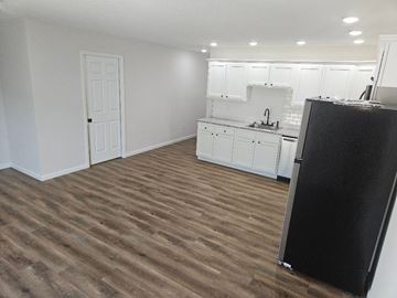 Lima apartment for rent - a kitchen with white cabinets and a black refrigerator