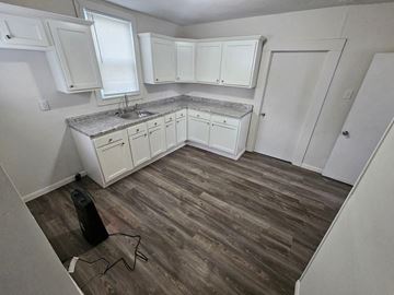 Lima house for rent - A kitchen with white cabinets and a wooden floor.