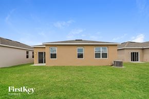 Bartow house for rent - a beige house with a grass yard and a grill