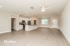 Palm Bay house for rent - A spacious living room with a kitchen in the background and a ceiling fan above.