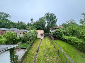 Clairton house for rent - A view of a green yard with a fence and a building in the background.