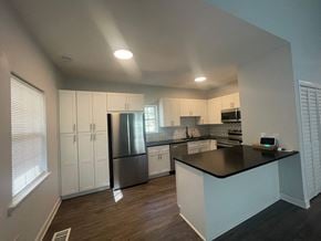 Atlanta house for rent - a kitchen with white cabinets and a black counter top